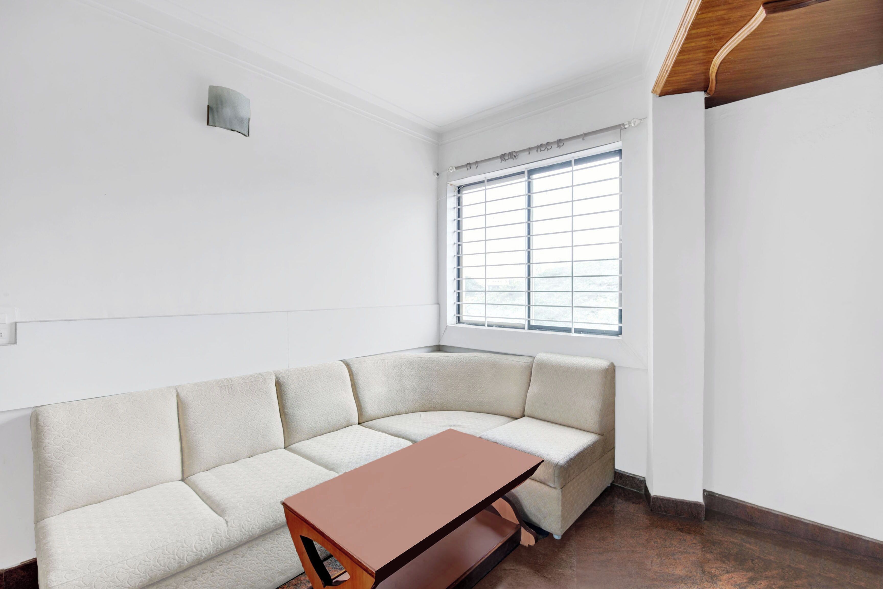 A corner room with a white textured sofa, a wooden table, and a window with blinds.