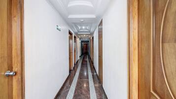 A hotel corridor with wooden doors, white walls, and a marble floor.