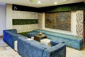 Una sala de estar moderna con sofás azules, una mesita y paneles decorativos en la pared.
