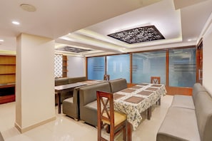 Un comedor moderno con una mesa larga, asientos acolchados y un panel decorativo en el techo.
