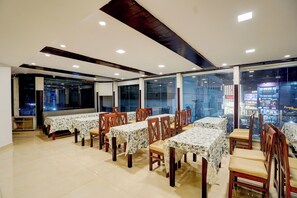 Un comedor con varias mesas y sillas, ventanas amplias y vistas a la ciudad.