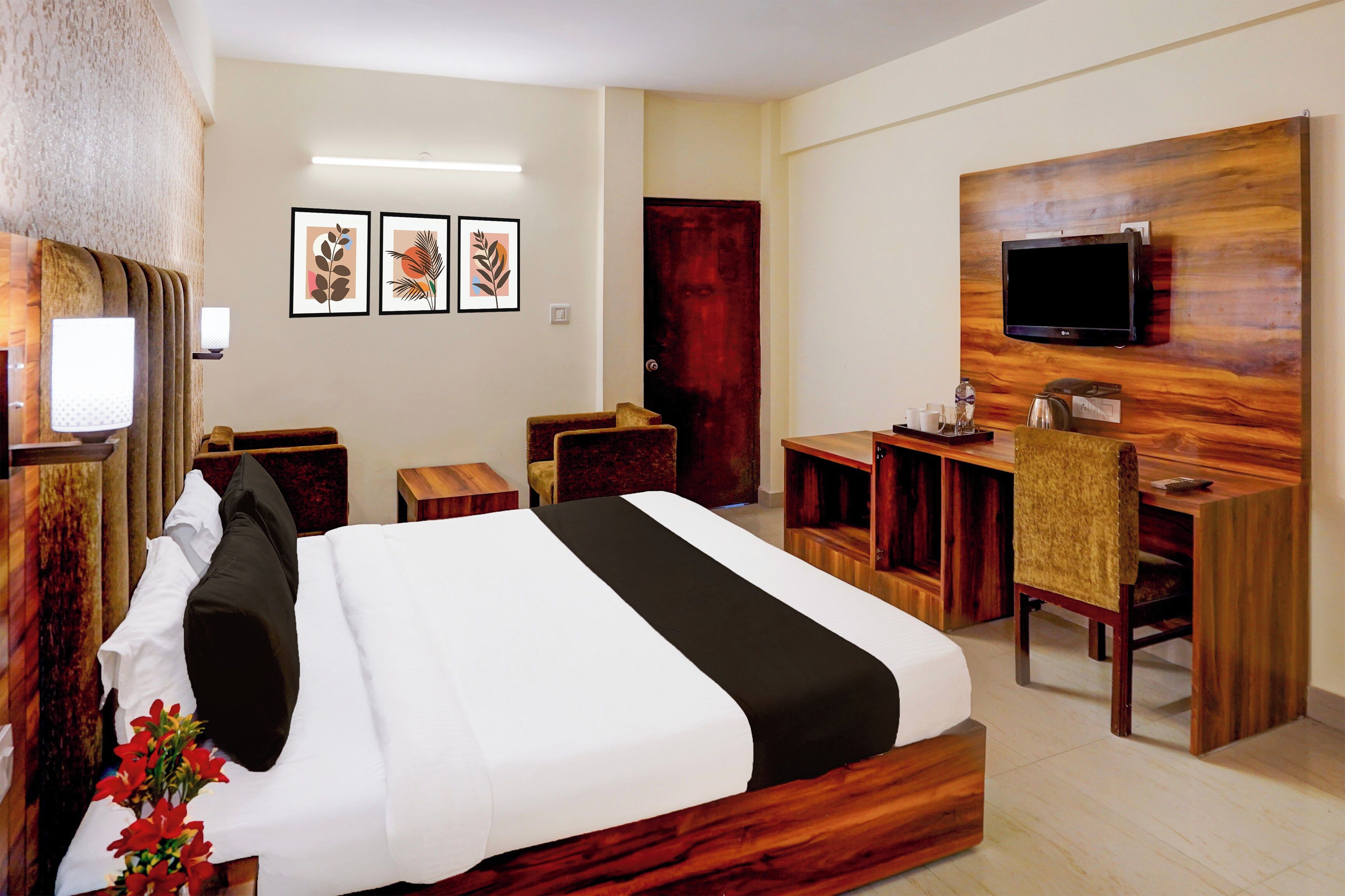 Una habitación de hotel con cama, escritorio, silla, televisor y cuadros en la pared.