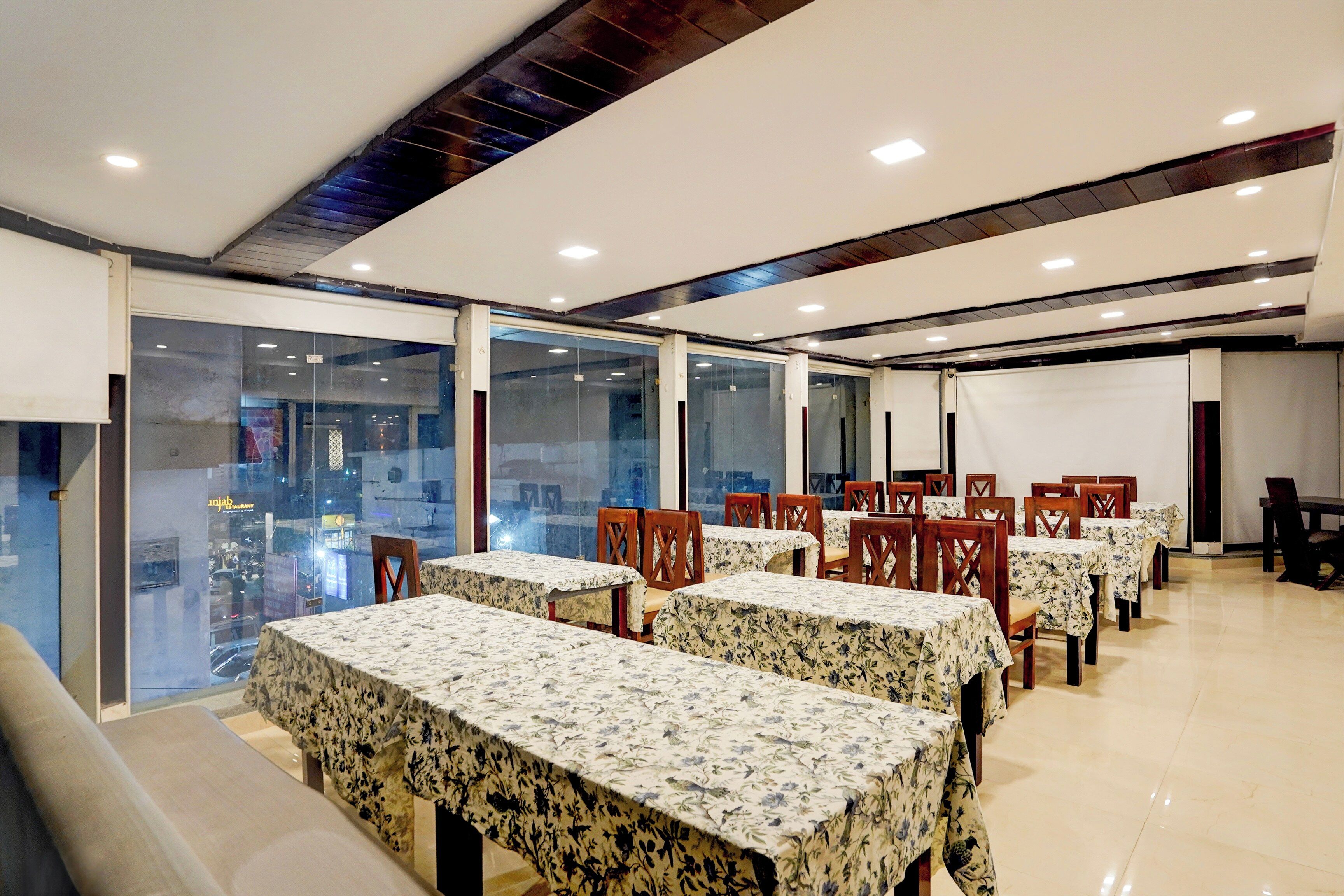 Un comedor con mesas y sillas, ventanas amplias y vista a la calle.