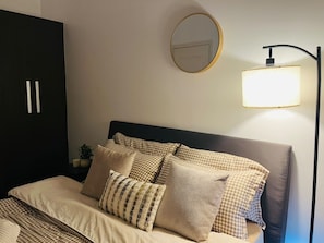 Ein Schlafzimmer mit Bett, Kissen, einem Nachttisch mit Lampe und einem Kleiderschrank.