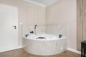 A bathroom with a freestanding bathtub filled with bubbles, a showerhead, and a toilet. - Kielce | Żelazna 43 | Modern Apartment | Whirlpool Bath (Kielce)