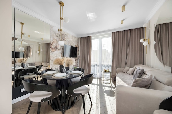 A modern living room with a dining area, a sofa, and a TV.