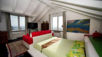 Une chambre à coucher avec un lit, une télévision, un tableau et une vue sur la mer.