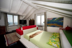 Ein Schlafzimmer mit Bett, Fernseher, einem Gemälde und Meerblick.