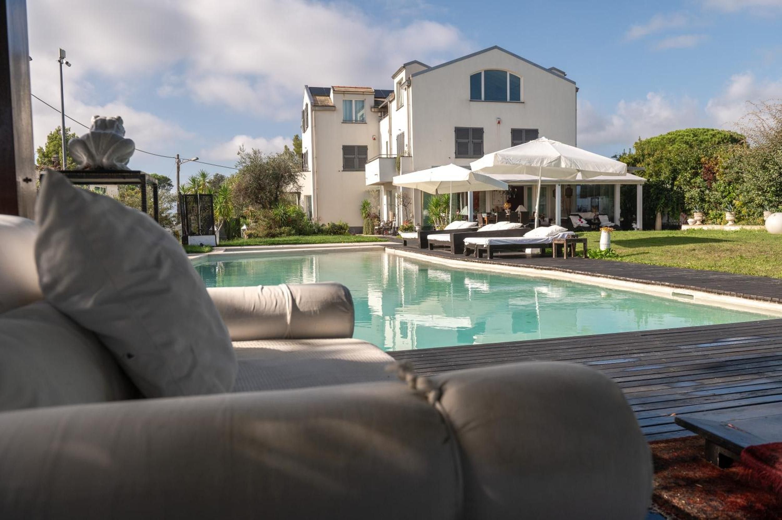 Een zwembad met ligbedden en parasols, een gebouw met balkon, en een heldere lucht.