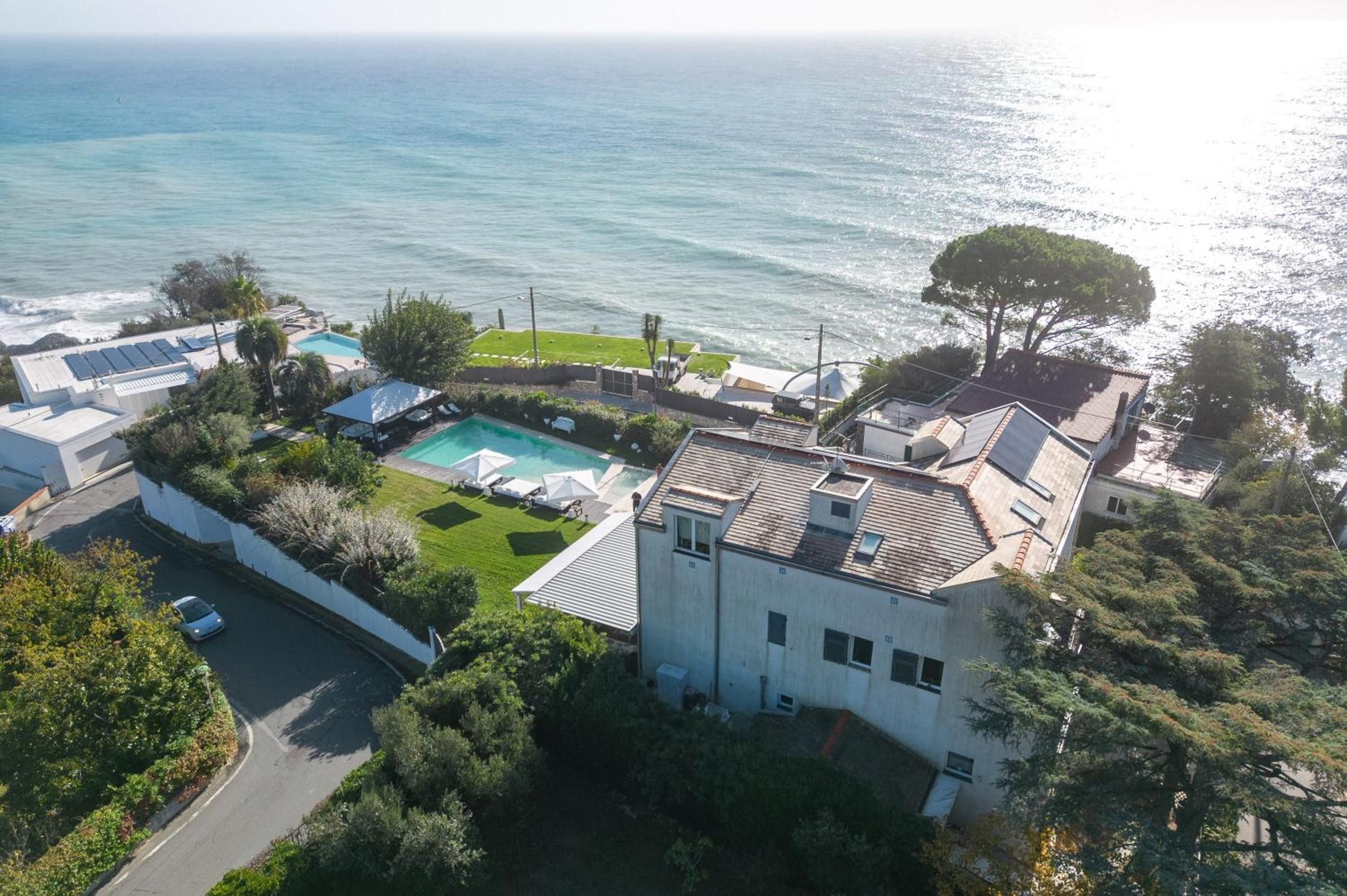 Une propriété résidentielle dotée d’une piscine, d’un court de tennis et offrant une vue sur la mer.