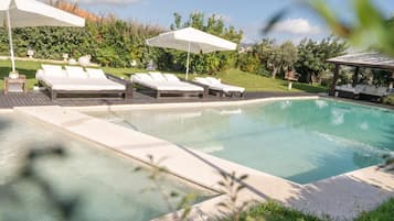 Ein Poolbereich mit Liegestühlen und Sonnenschirmen.