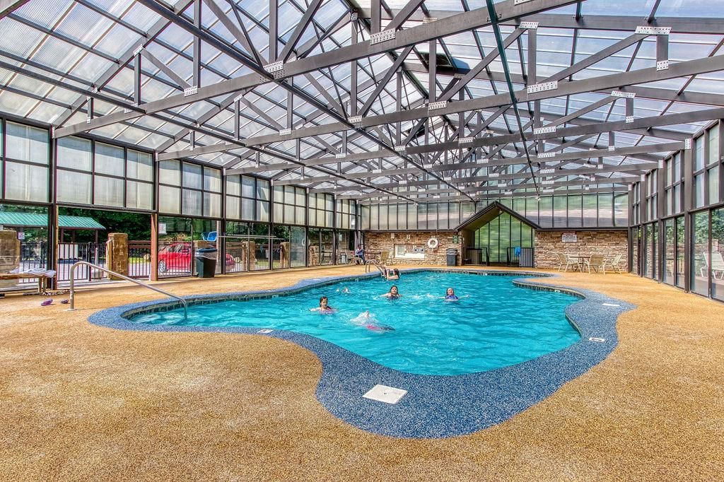 Ein Hallenbad mit Glasdecke, umgeben von einem bodennahen pebble-Boden und einer Steinsäule im Hintergrund.