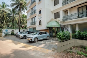 A hotel with a sign reading 'staymaster veridian,' a parking area with several cars, and a building with balconies and a green awning. - Staymaster Veridian (Goa)