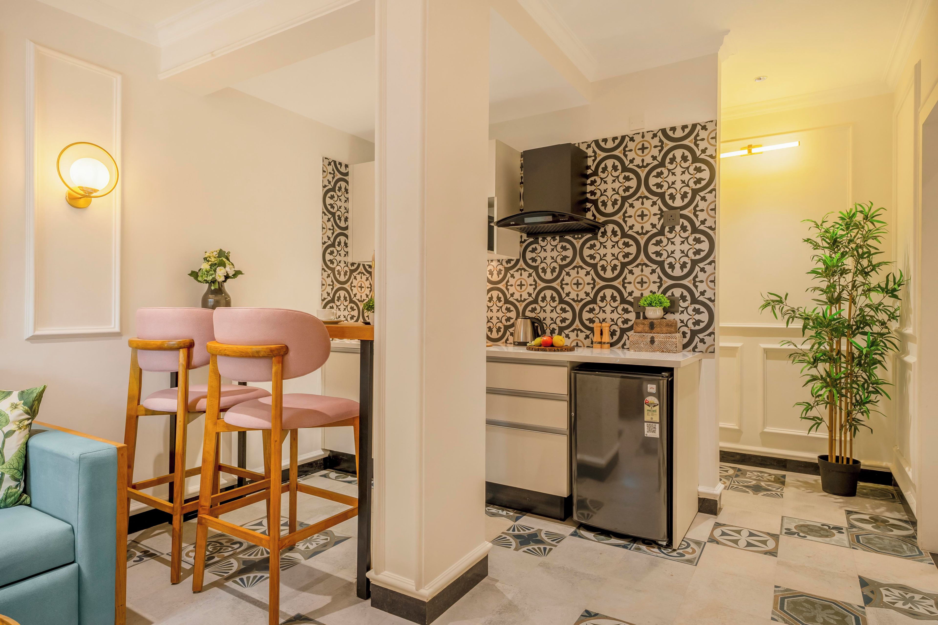 Une cuisine moderne équipée d’une cuisinière intégrée, d’un réfrigérateur et d’un crédence décorée. On y trouve également un coin salon avec un canapé bleu et des chaises en bois.