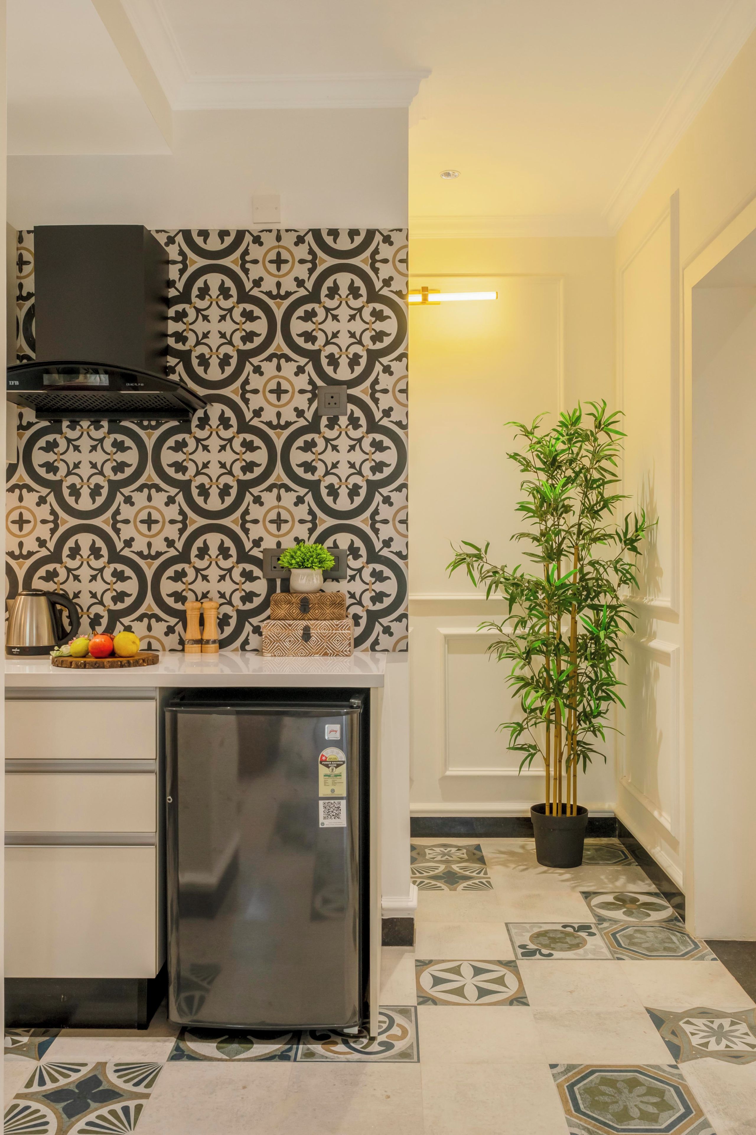 Una cocina compacta con un salpicadero estampado, un refrigerador integrado y una planta en maceta.