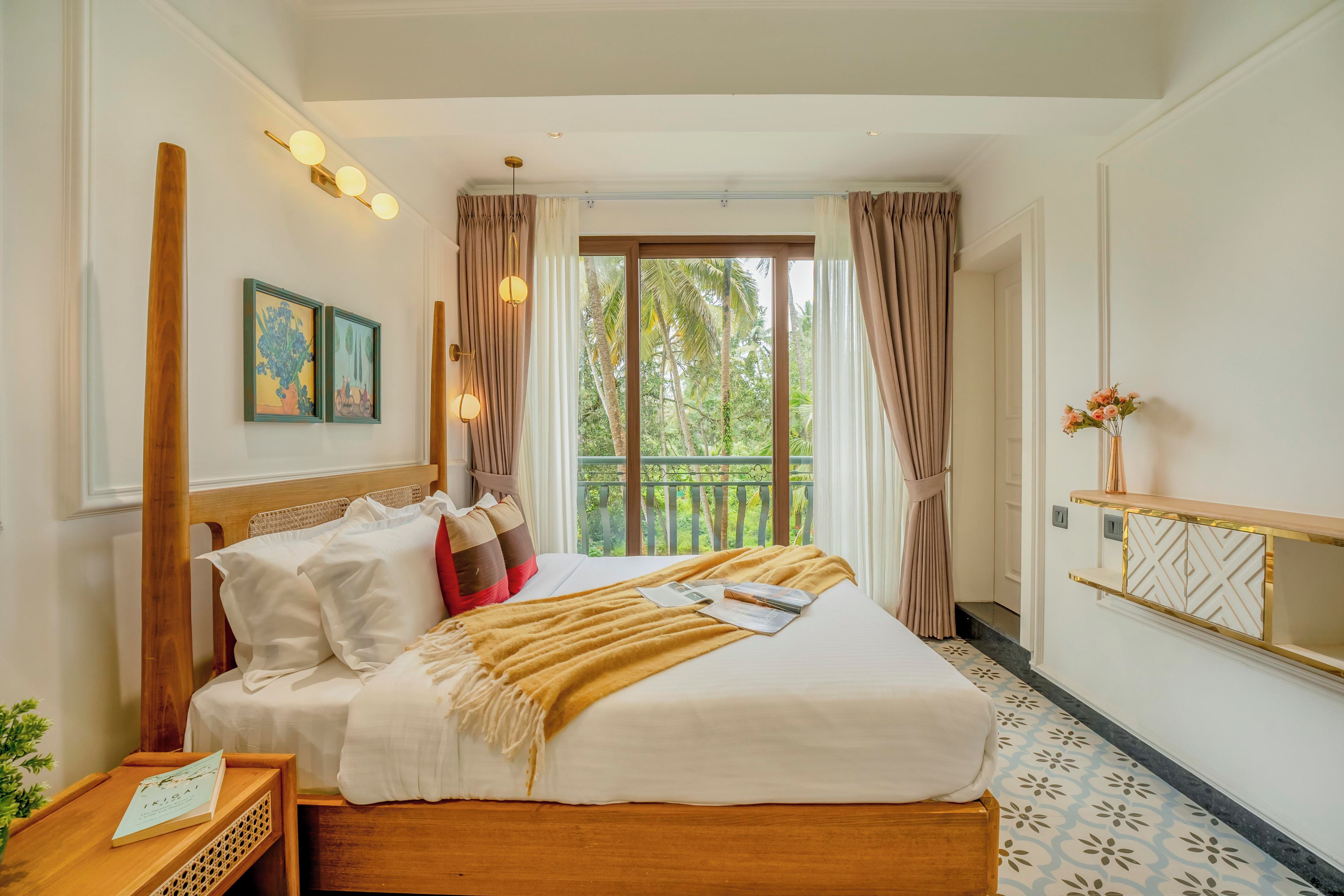 Une chambre d’hôtel avec un lit, une table de chevet, une fenêtre avec des rideaux et une vue sur la verdure.