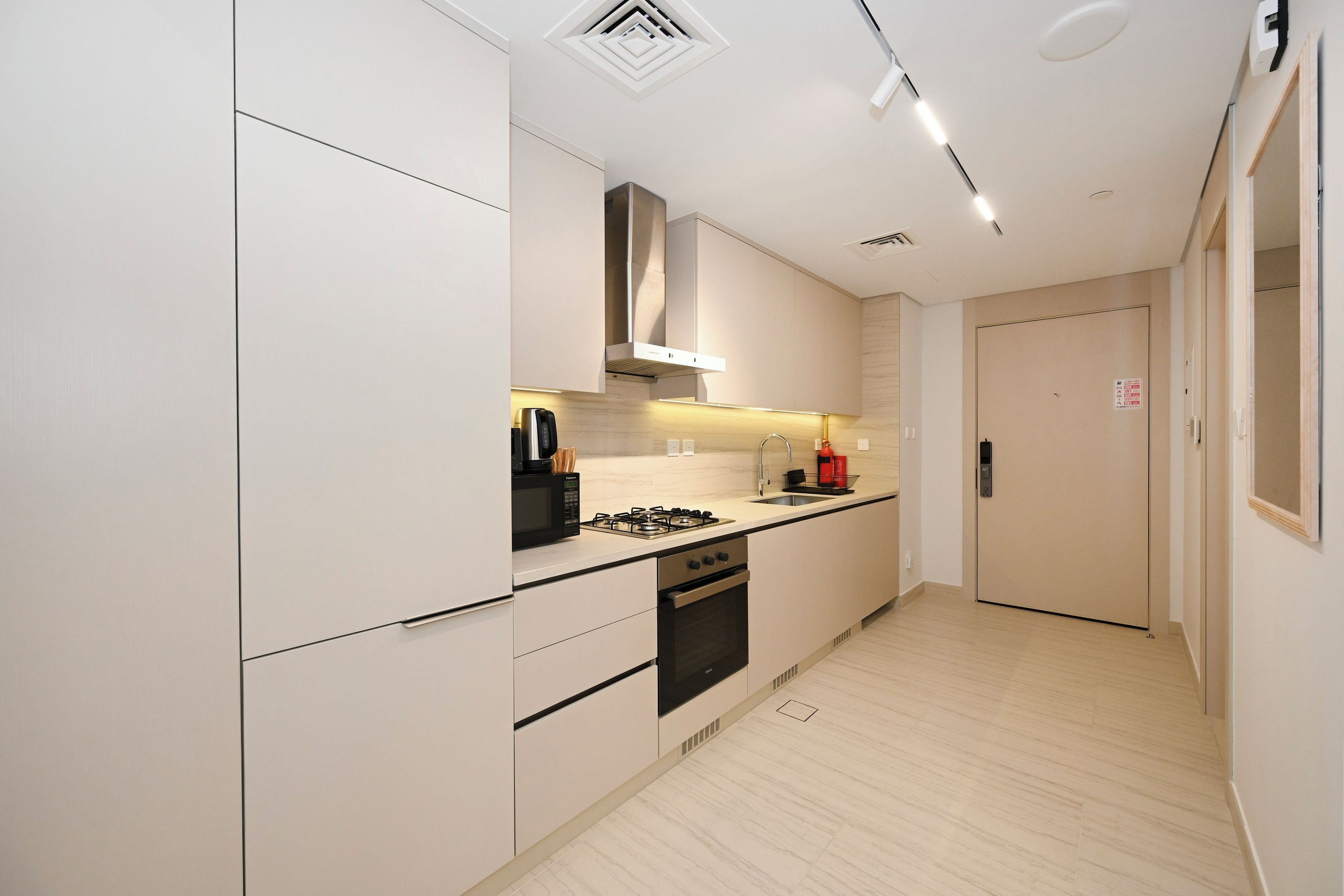 A modern kitchen with white cabinetry, a gas stove, a microwave, and a built-in oven.