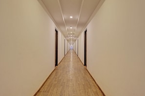 A long, narrow hotel corridor with wooden flooring and white walls. - Townhouse Ramamurthy Nagar (Bangalore)