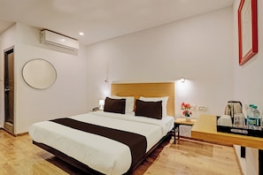 A hotel room with a bed, bedside table, lamp, and a wall-mounted air conditioner. - Townhouse Ramamurthy Nagar (Bangalore)