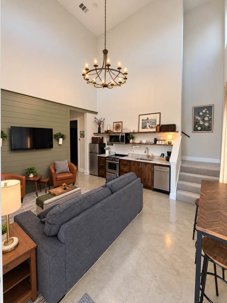 A modern living room with a sofa, a dining table, and a kitchen in the background.