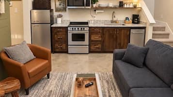 Une cuisine moderne équipée d’un four encastré, d’un micro-ondes et d’un réfrigérateur. On y trouve également un coin repas avec un canapé et une table basse.