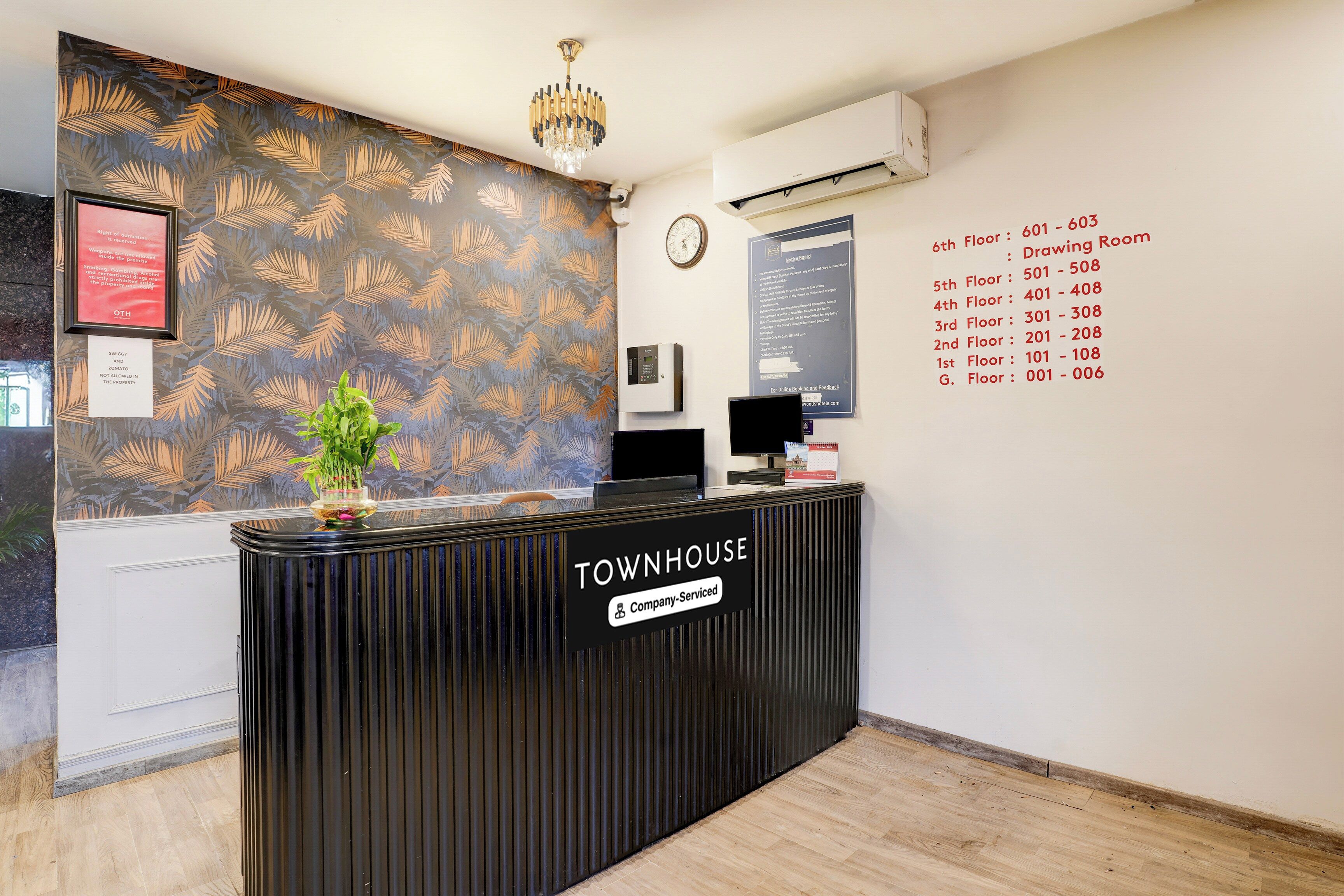 A reception desk with a 'Townhouse' sign, a clock, and a notice board listing room numbers and services.