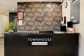A reception desk with a 'TOWNHOUSE' sign, a notice board, and a clock. - Townhouse Ulsoor Near Halasuru Metro (Bangalore)