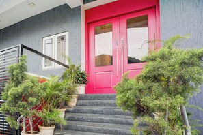 A building with a bright pink door, a staircase leading to the entrance, and potted plants around the steps. - Townhouse Ulsoor Near Halasuru Metro (Bangalore)