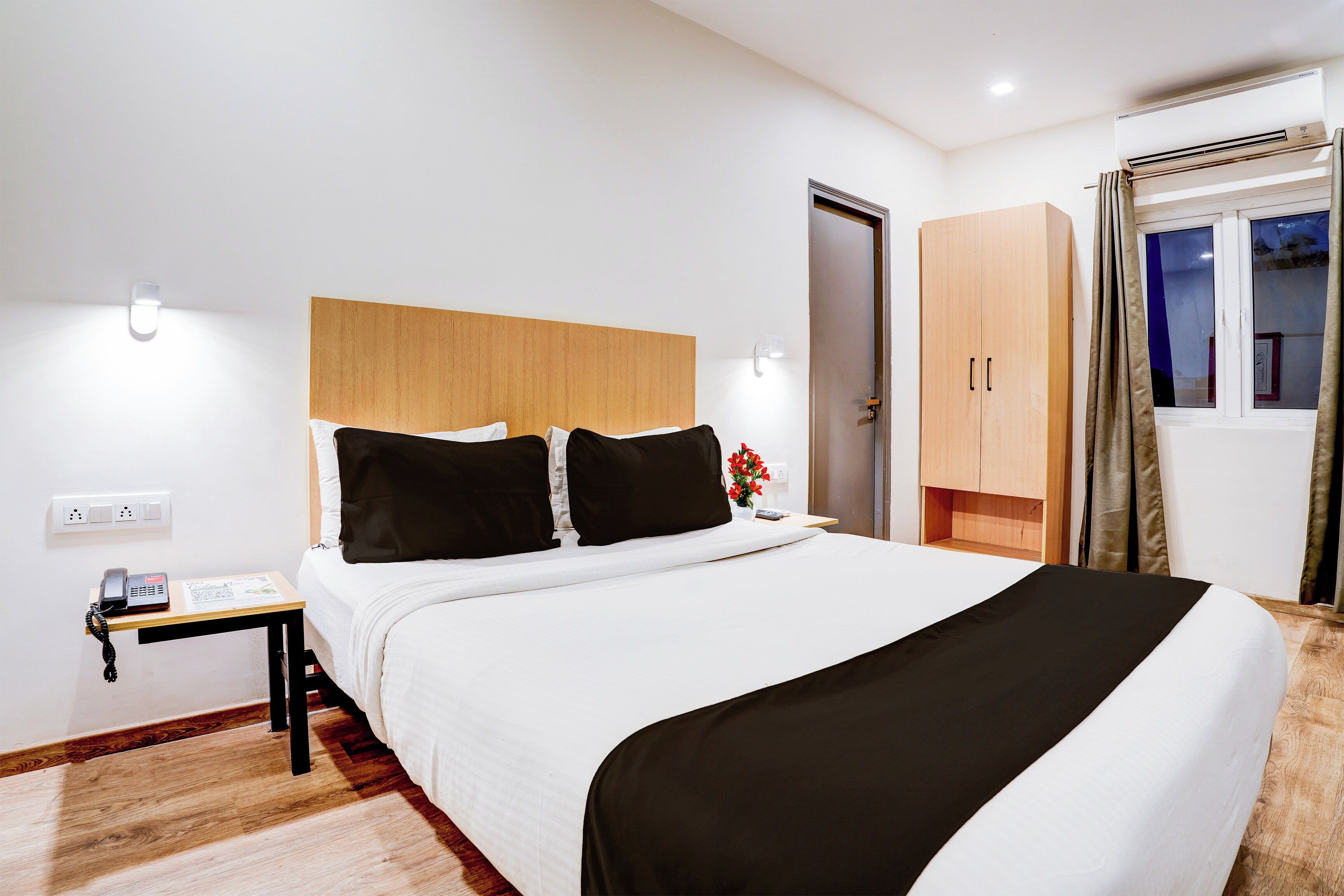 A hotel room with a bed, bedside table, and a wardrobe.