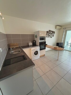 A compact kitchen with a built-in washer, a microwave, and a toaster. - Caribbean Getaway in Le Gosier, Sea View • Pool • WiFi • Near Restaurants (Le Gosier)