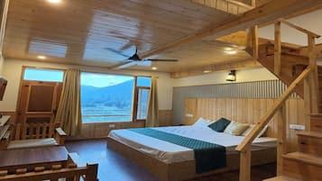 Interior de una cabaña de madera con una cama, un escritorio y una escalera.