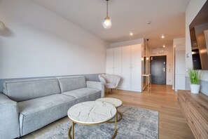 A modern living room with a grey sofa, a marble coffee table, and a small round table. - RentPlanet - Apartamenty Wydmowa (Kołobrzeg)
