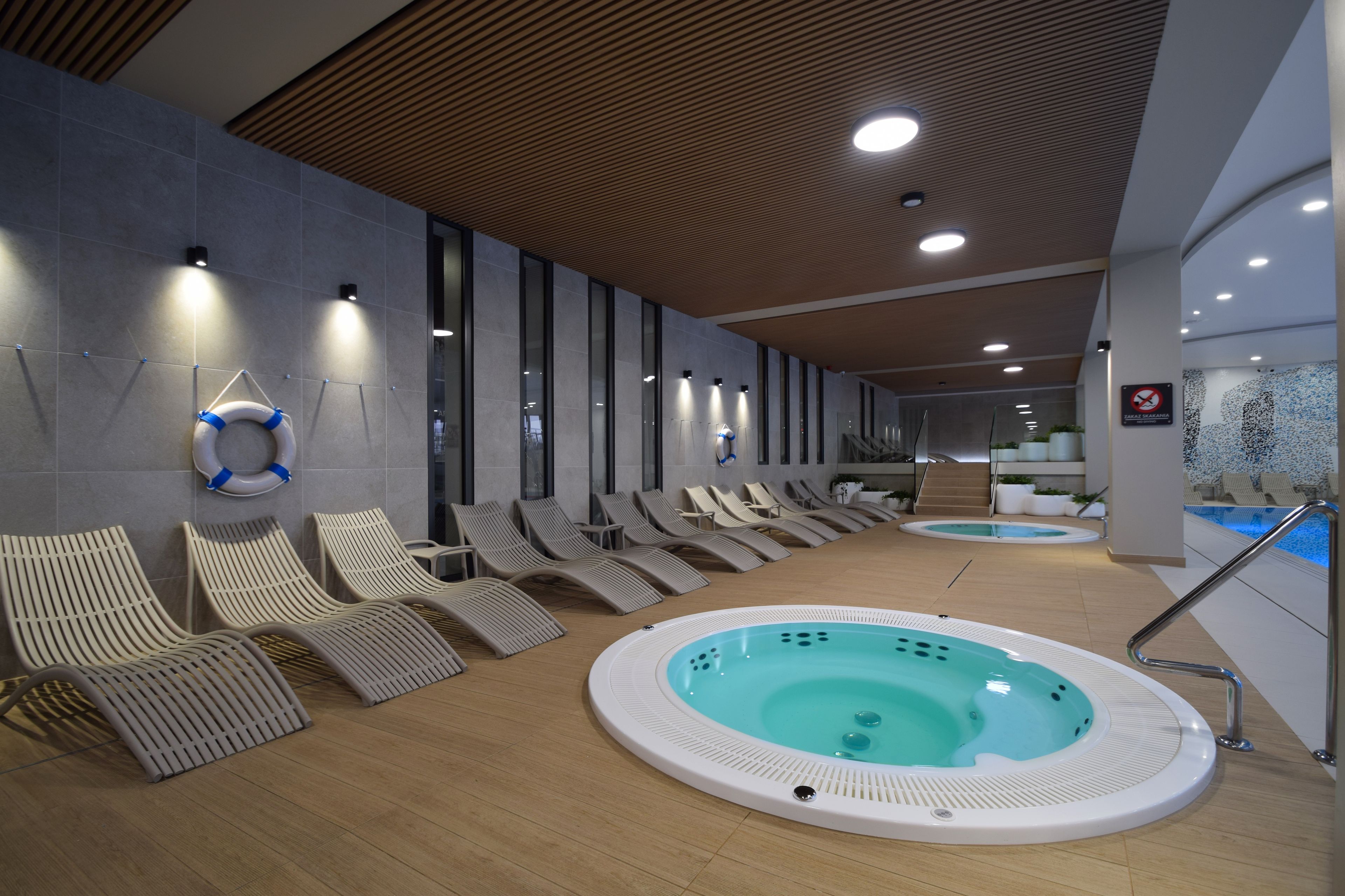 Ein moderner Innenbereich mit Schwimmbad, Liegestühlen und einem Whirlpool.