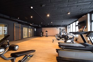A gym with various exercise equipment, including treadmills and stationary bikes, and a wooden floor. - RentPlanet - Apartamenty Wydmowa (Kołobrzeg)