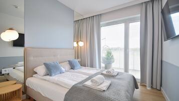 A hotel room with a bed, bedside table, and a TV mounted on the wall.