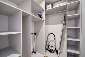 A storage closet with shelves, a vacuum cleaner, and a laundry basket. - RentPlanet - Apartamenty Wydmowa (Kołobrzeg)