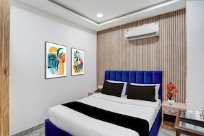 A hotel room with a bed, a nightstand, an air conditioning unit, and two framed artworks on the wall. - Townhouse by OYO Mohali Bus Terminal (Mohali)