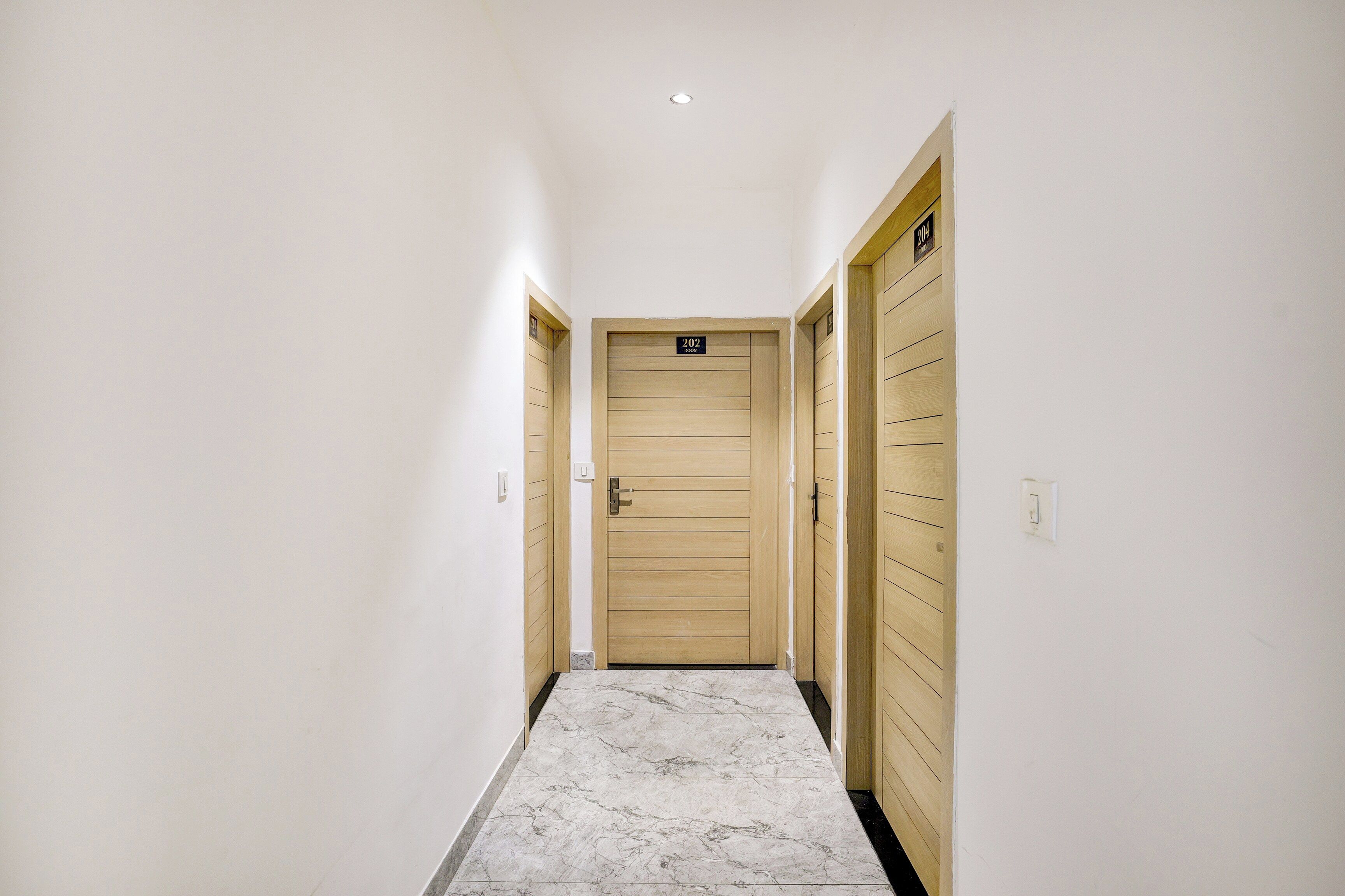 A hallway with a wooden door labeled '202' and a marble floor.