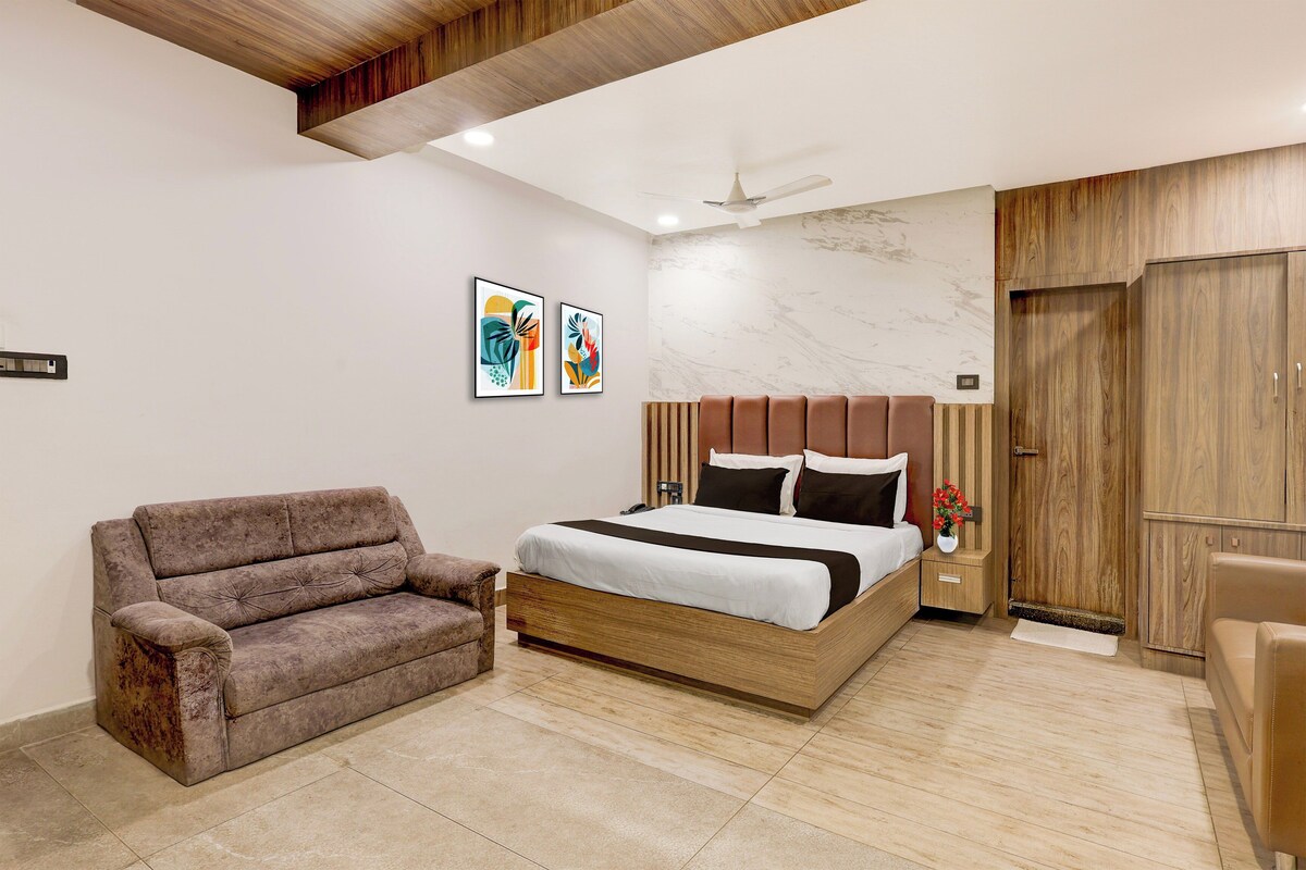 A bedroom with a bed, a chair, a nightstand, a ceiling fan, and a wooden wardrobe.