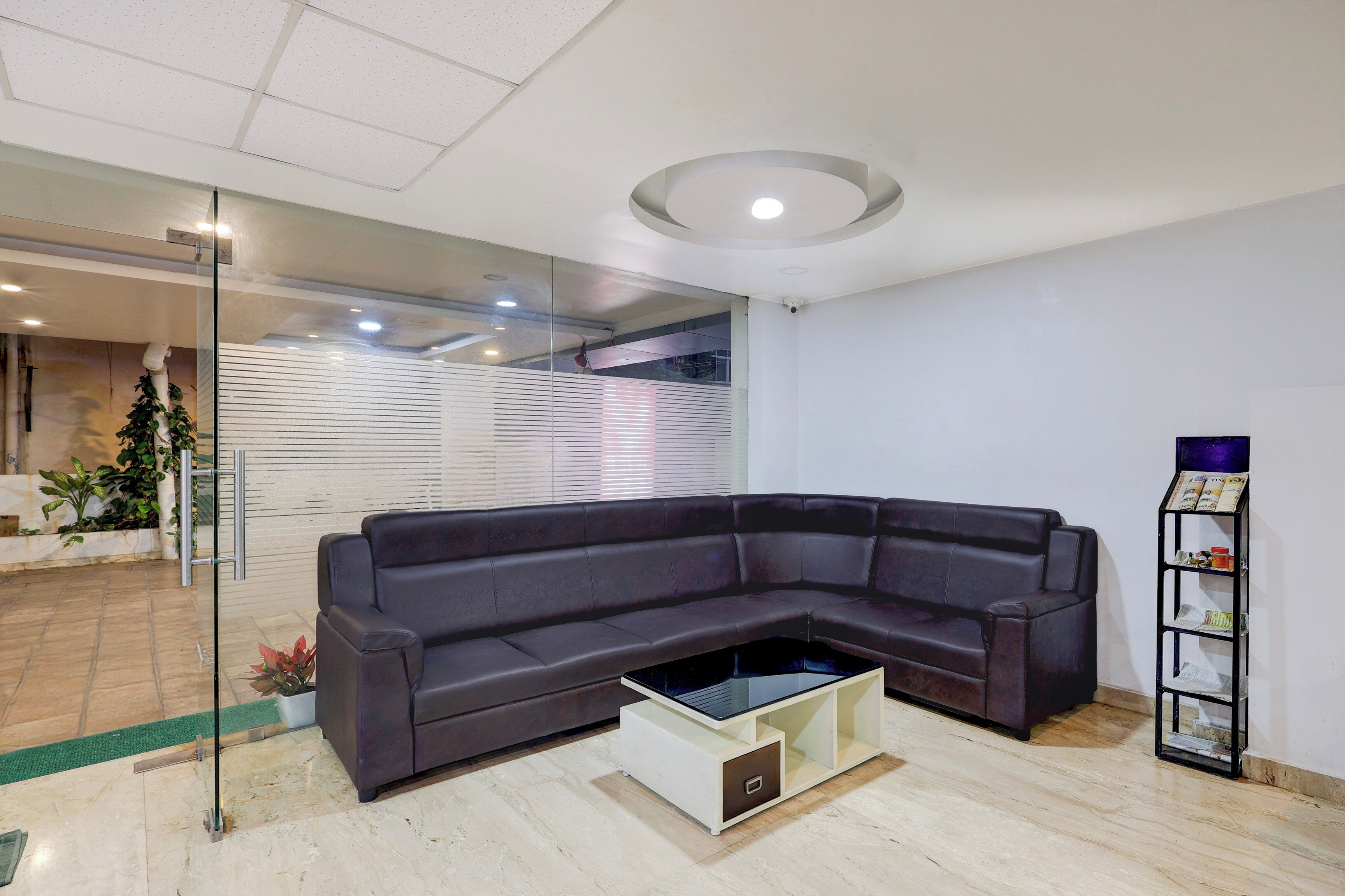 A modern living room with a sectional sofa, a glass coffee table, and a small bookshelf.