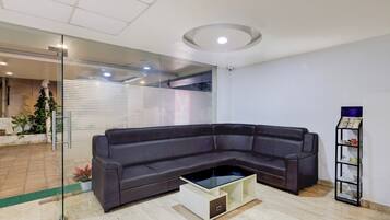 A modern living room with a sectional sofa, a glass coffee table, and a small bookshelf.