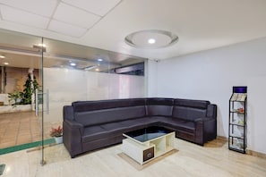 Una sala moderna con un sofá modular, una mesa de centro de vidrio y una pequeña estantería.