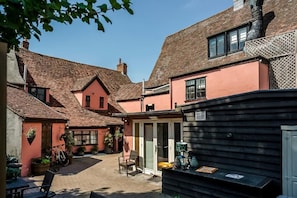 A courtyard with a seating area, a bicycle, and a small structure with a bench. - The Old Bull Inn at Alaz (Sudbury)
