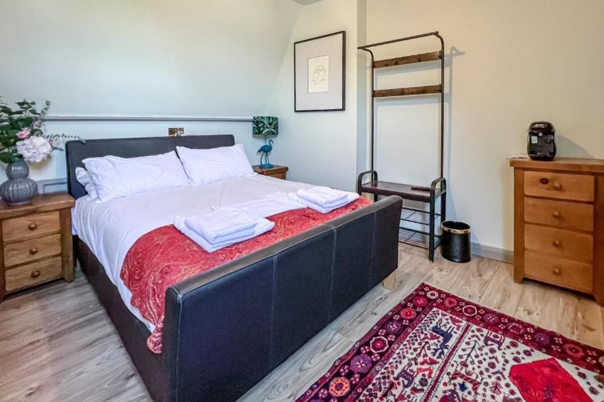 Een slaapkamer met een bed, nachtkastjes, een kaptafel, een spiegel en een vloerkleed.