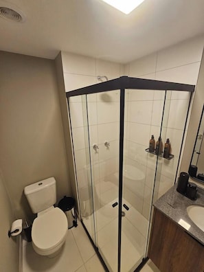 Ein modernes Badezimmer mit einer gläsernen Duschkabine, einer Toilette und einem Waschbecken.
