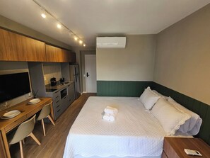 Ein Hotelzimmer mit einem Bett, einem Schreibtisch, einer Küchenzeile und einer Klimaanlage.