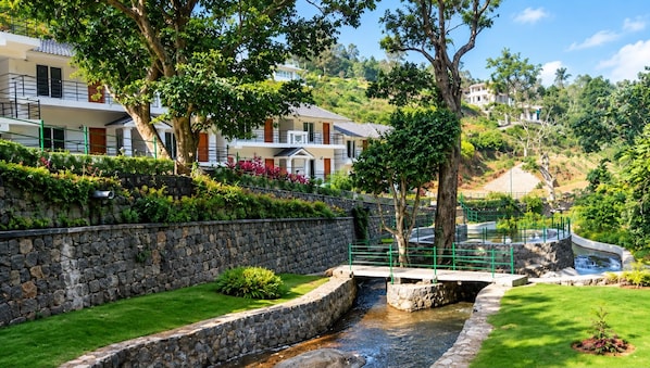 Un barrio residencial con un muro de piedra, un pequeño arroyo y un puente.
