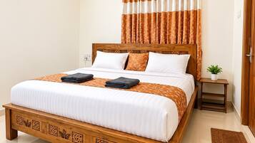 A bedroom with a bed, a ceiling fan, a nightstand, and a potted plant.