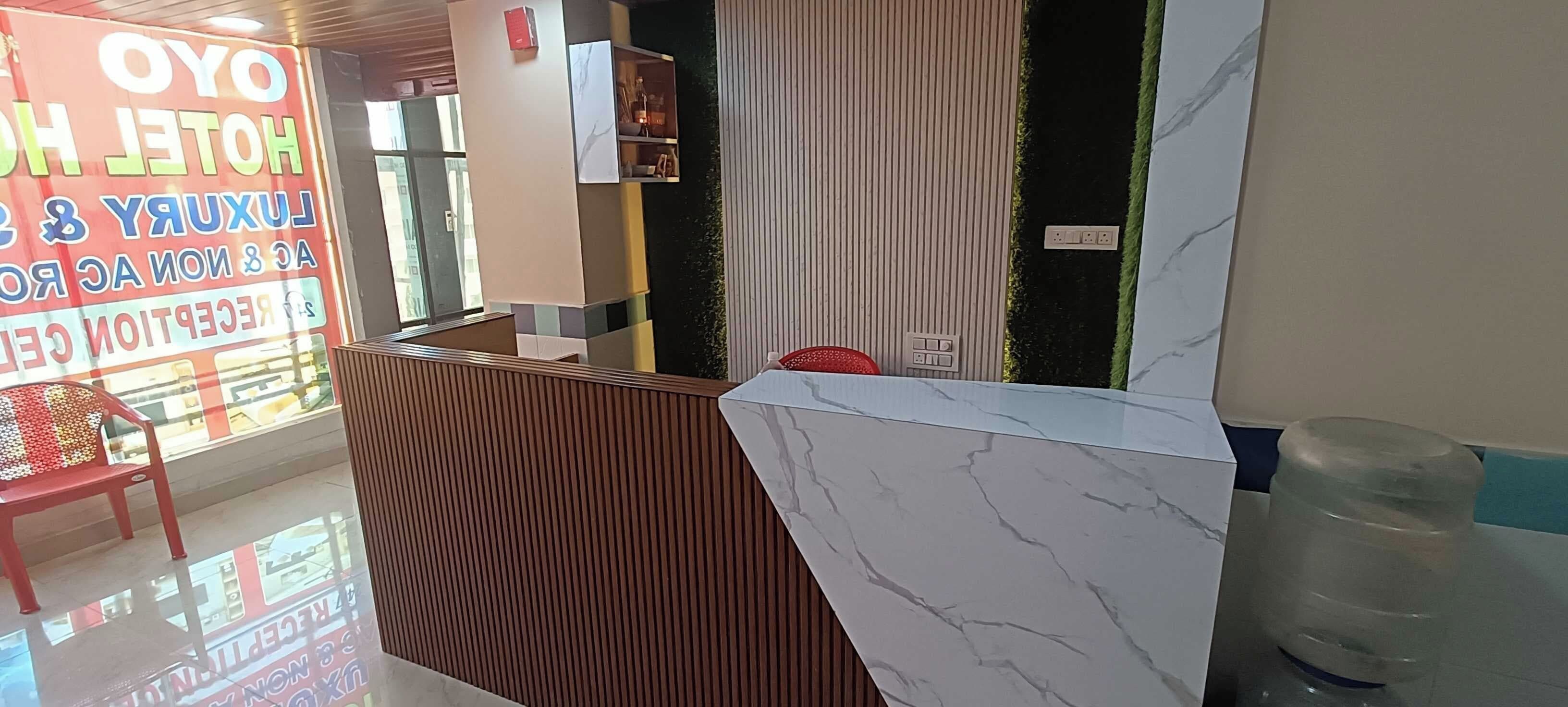A hotel reception area with a wooden reception desk, a water dispenser, and a red chair.