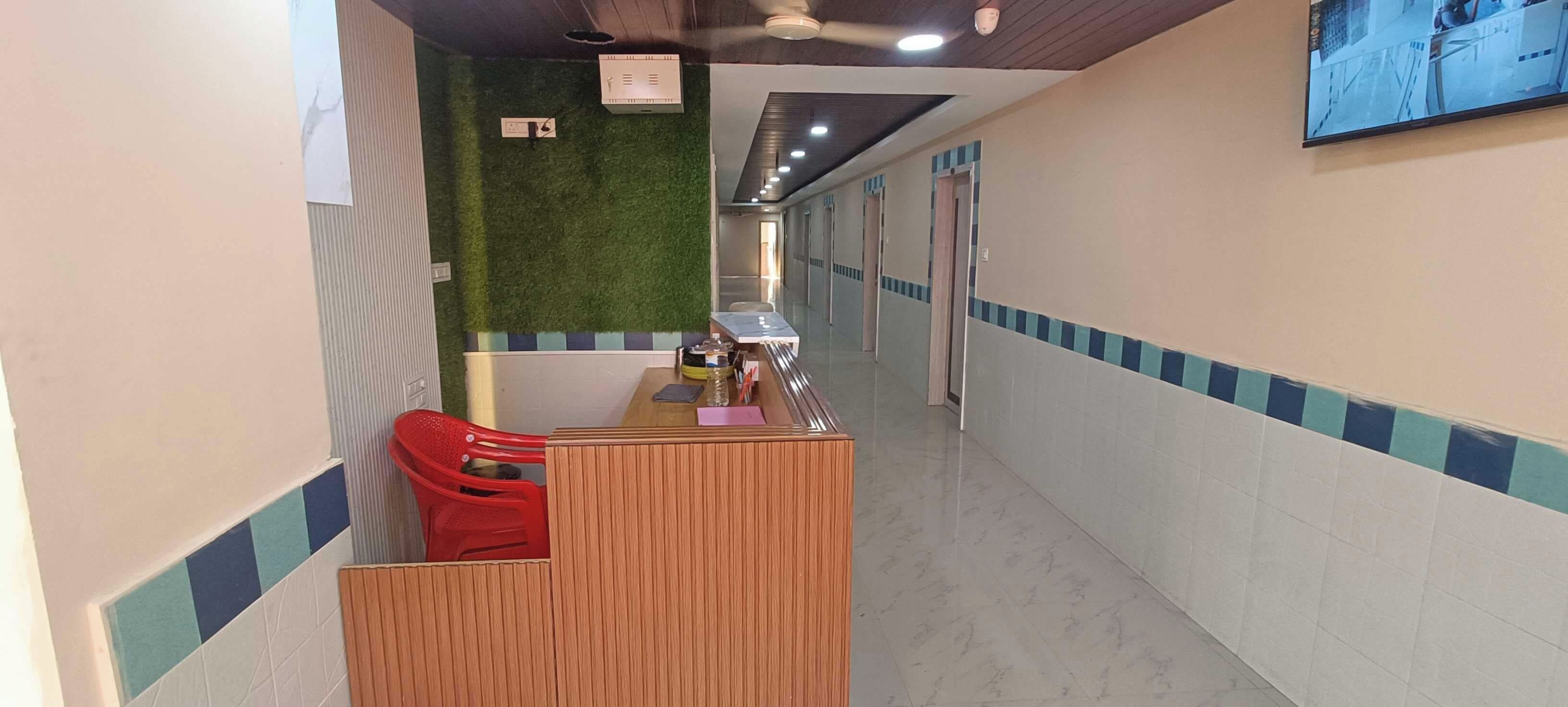 Una zona de recepción con un escritorio de madera, una silla roja y una pared verde.